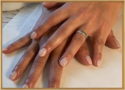 Due mani con una manicure nude, una sull'altra, con un anello d'argento.